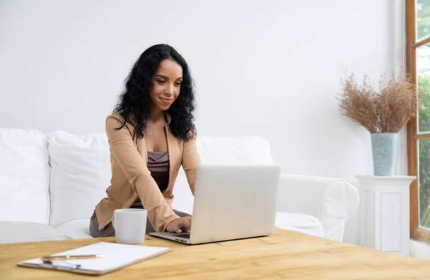 Afroamerykanka używająca laptopa do kluczowych prac w Internecie. Sekretarz lub pismo online pracujące w domu. - Zdjęcie, obraz