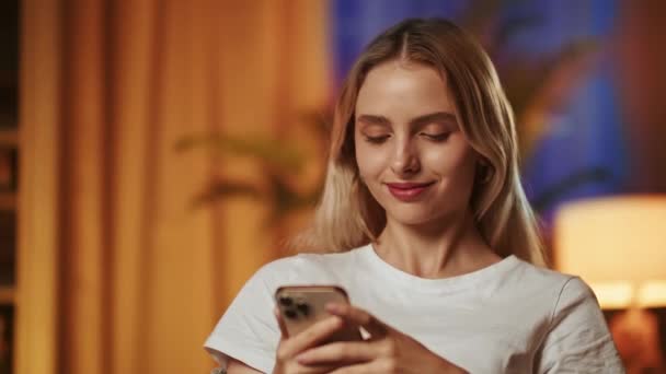 Усміхнена красива блондинка використовує смартфон, насолоджується читанням смішних історій або жартів. Молода леді з щасливим задоволеним обличчям і похмурий погляд отримує повідомлення про покарання - Кадри, відео