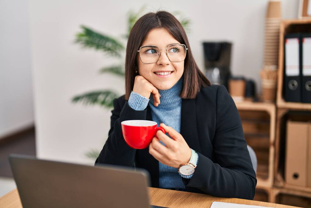 Fiatal gyönyörű spanyol nő üzleti dolgozó használja laptop kávézás az irodában - Fotó, kép