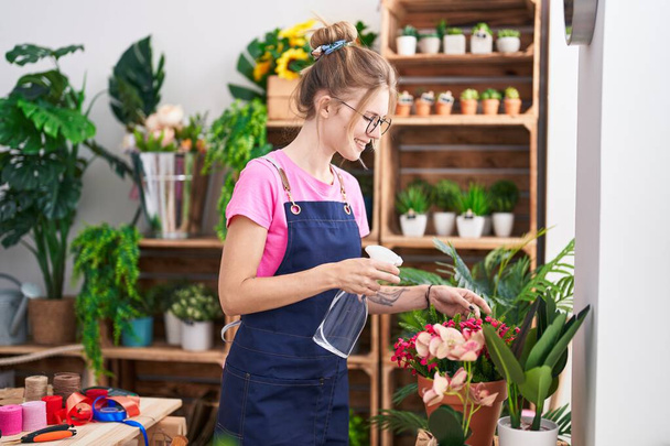 Giovane donna bionda fiorista utilizzando diffusore di lavoro sorridente al negozio di fiori - Foto, immagini