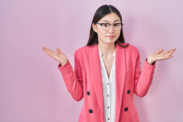 メガネをかけた中国のビジネス若い女性は,手を挙げて腕と手で混乱した表情をしました. 疑似コンセプト.  - 写真・画像