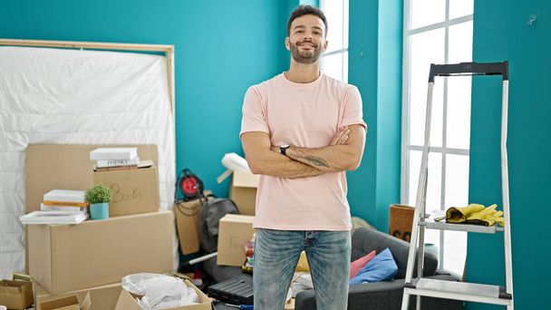 Young hispanic man smiling confident standing with arms crossed gesture at new home - Photo, Image