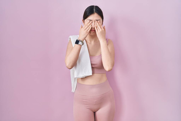 Mujer joven china con ropa deportiva y toalla frotando los ojos para la fatiga y el dolor de cabeza, la expresión somnolienta y cansada. problema de visión  - Foto, imagen