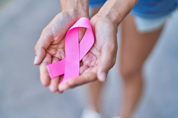 Young blonde woman holding pink ribbon at street - Photo, image