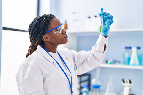 Африканська жінка-науковець, яка тримає пробірку в лабораторії. - Фото, зображення