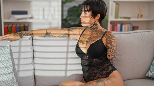 Latino nainen amputoitu käsi yllään alusvaatteita istuu sohvalla kotona - Valokuva, kuva