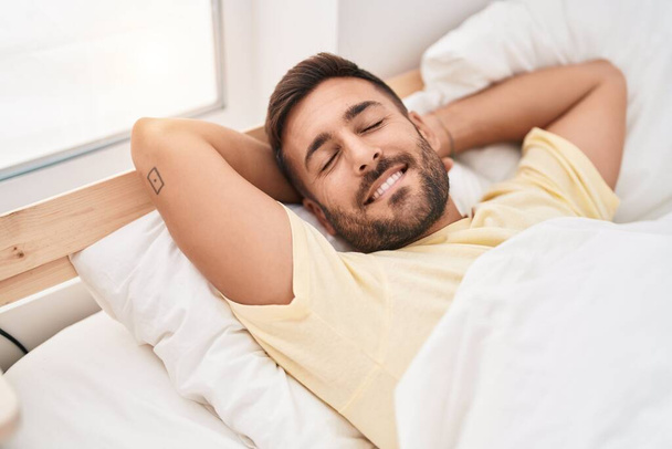 jonge latino man liggend op bed slapen in slaapkamer - Foto, afbeelding