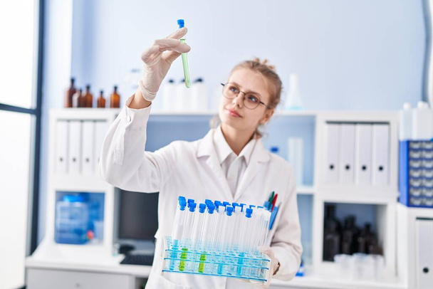 Nuori blondi nainen tiedemies, jolla on koeputkia laboratoriossa - Valokuva, kuva