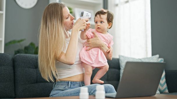 Mutter und Tochter mit Laptop bei Online-Kinderarzt-Beratung zu Hause - Foto, Bild