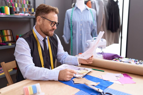 Homem de meia idade alfaiate procurando design de roupas no atelier - Foto, Imagem