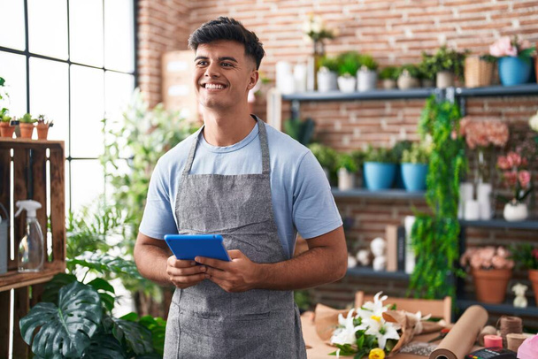 Young hispanic man florist smiling confident using touchpad at flower shop - Photo, Image