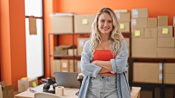 Young blonde woman ecommerce business worker standing with arms crossed gesture at office - Photo, Image