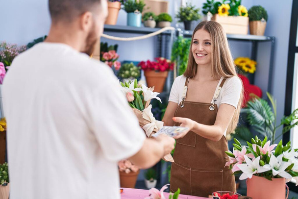 Man and woman customer paying for boquet of flowers at flower shop - Photo, Image