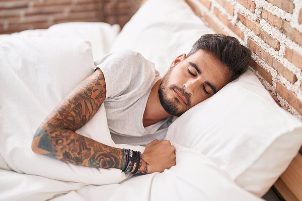 Молодий іспаномовний чоловік лежить на ліжку спить у спальні
 - Фото, зображення