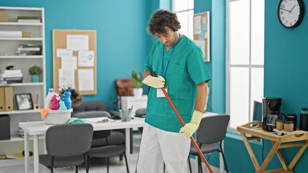 Genç İspanyol profesyonel temizlikçi ofiste yerleri temizliyor. - Fotoğraf, Görsel
