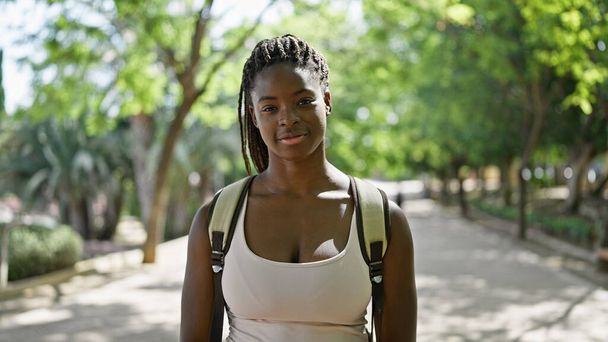 Donna afroamericana turista che indossa lo zaino sorridente al parco - Foto, immagini