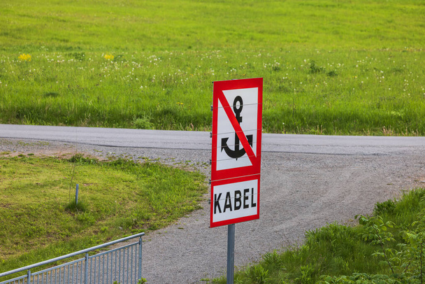 Close-up view of sign prohibiting anchoring boats in Swedish, set against green grass lawn background.  - Photo, Image