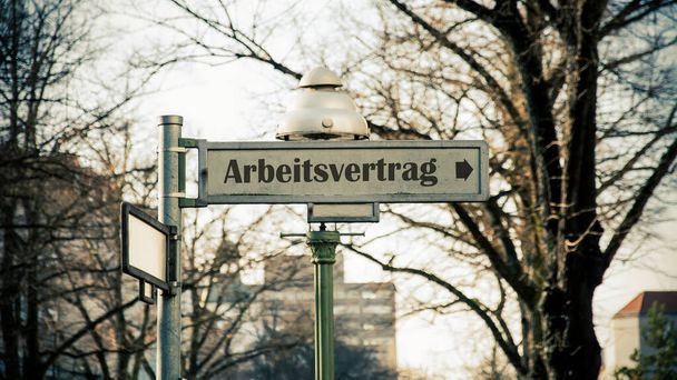 Image shows a signpost and a sign in the direction of an employment contract in German. - Photo, Image