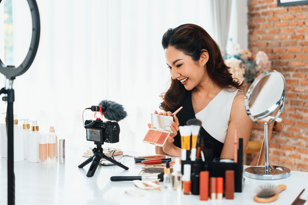 Woman influencer shoot live streaming vlog video review makeup uttermost social media or blog. Happy young girl with cosmetics studio lighting for marketing recording session broadcasting online. - Photo, Image