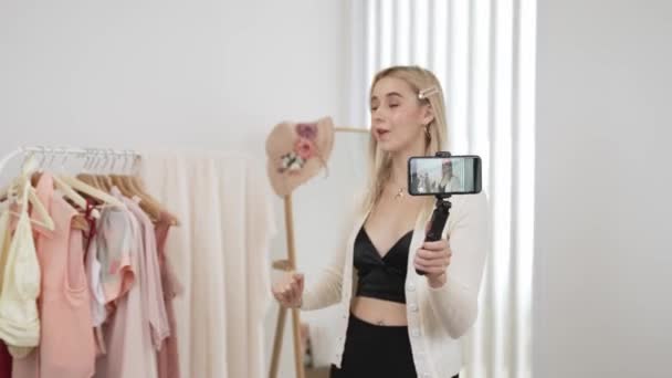 Jeune créateur de contenu social médial femme faire de la vidéo de mode à l'aide de selfie stick. Blogueur sourire à la caméra tout en faisant des vêtements en ligne persuasif vendre vlog à l'auditoire ou suiveur. Blithe - Séquence, vidéo