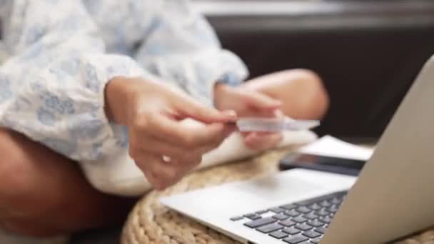 Młoda kobieta korzystająca z laptopa z kartą kredytową do bankowości internetowej, zakupów online E-commerce przez bramę płatności online w domu. Nowoczesne i wygodne zakupy online z kartą debetową. Blithe - Materiał filmowy, wideo