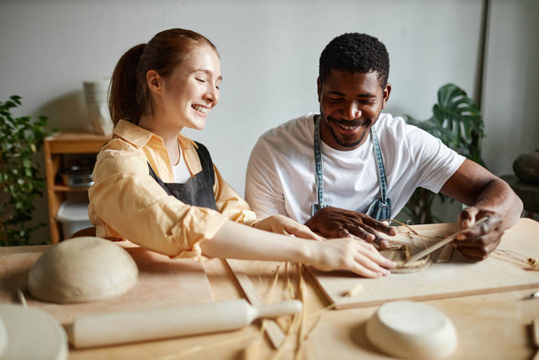 Retrato de pareja joven despreocupada disfrutando de taller de cerámica juntos y haciendo cerámica hecha a mano - Foto, imagen