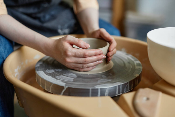 Close up de mulher jovem usando roda de cerâmica e criando cerâmica artesanal em estúdio acolhedor, espaço de cópia - Foto, Imagem