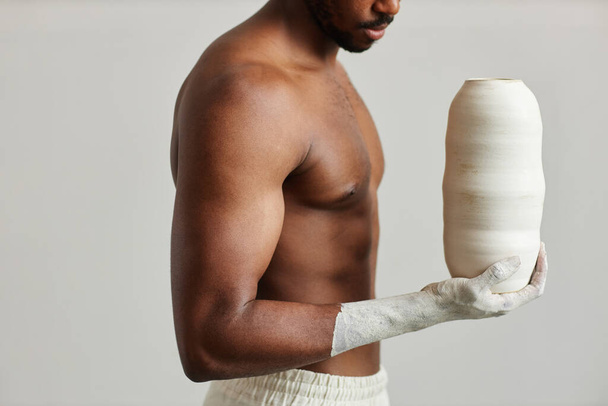 Minimaalinen laukaus lihaksikas musta mies tilalla käsintehty keraaminen maljakko, taiteen ja taiteilijan käsite - Valokuva, kuva