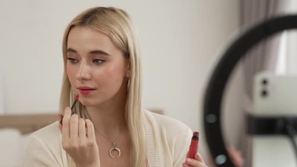 Young woman making beauty and cosmetic tutorial video content for social media. Beauty blogger using camera and light ring while showing how to apply liquid lipstick to audience or follower. Blithe - Footage, Video