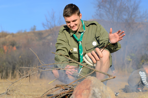 Boy Scout Cooking Sausages on Stick over Campfire - Foto, Imagen