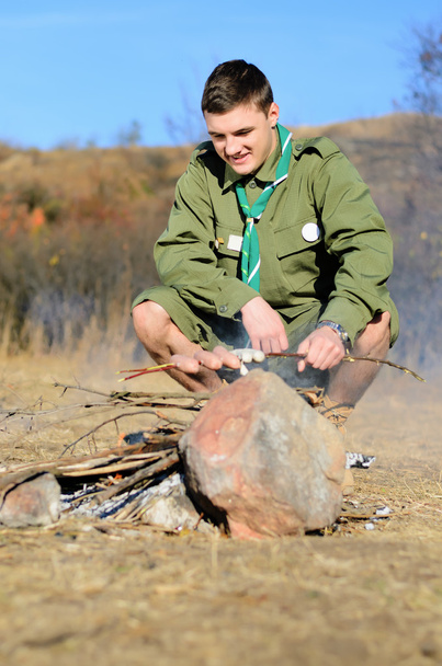 Boy Scout cocinar salchichas en palo sobre fogata
 - Foto, imagen