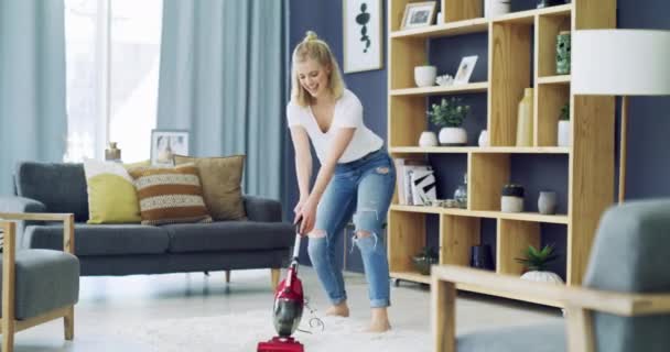 Woman, dancing and cleaning carpet with happy in living room, vacuum and housekeeping in home. Young person, cheerful and housework in lounge for carefree, relax wellness and weekend in apartment. - Footage, Video