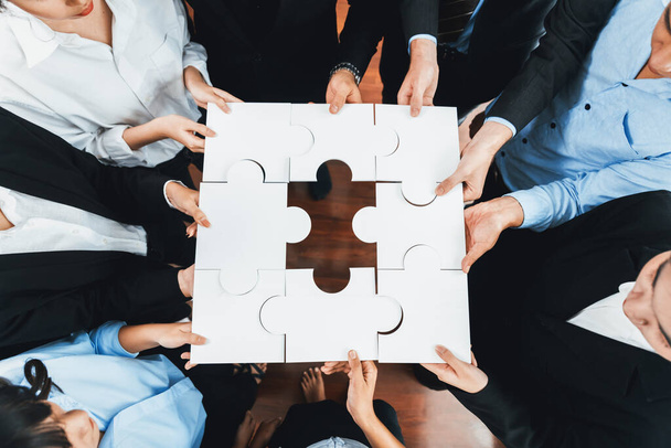 Von oben betrachtet halten multiethnische Geschäftsleute Puzzleteile und verschmelzen sie als effektive Lösung zur Lösung von Teamarbeit, gemeinsamer Vision und gemeinsamem Ziel, das unterschiedliche Talente vereint. Akribisch - Foto, Bild