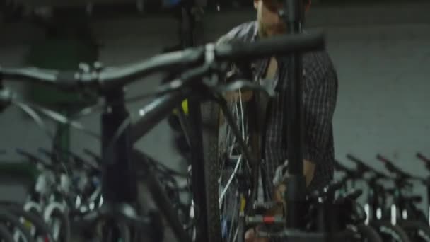 Câmera de mão tiro de homem removendo roda de bicicleta e caminhando enquanto trabalhava na oficina - Filmagem, Vídeo