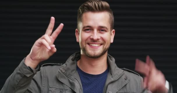 Portrait, smile and man with peace sign, agreement and feedback on a dark studio background. Face, person and model with hand gesture, review and support with vote, emoji and v symbol with icon. - Footage, Video