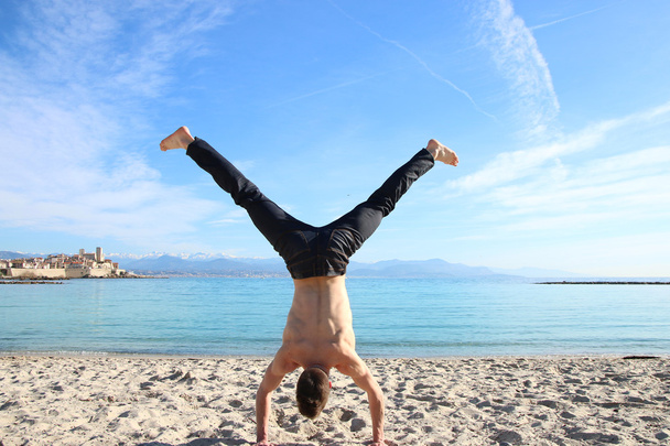 Человек делает стойку на руках на пляже
 - Фото, изображение