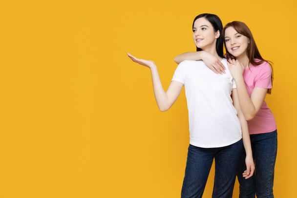 Twee zussen poseren op een gele achtergrond - Foto, afbeelding