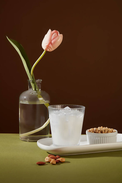 Una taza llena de leche y hielo poner en un plato con un tazón de soja. Se muestran pocas almendras y nueces de anacardo. Las nueces son extremadamente buenas para tu corazón. - Foto, imagen