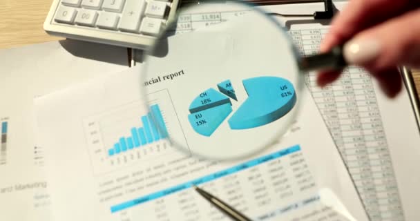 Manager hand holding magnifying glass over graph in financial report closeup 4k movie slow motion. Strategies in business development and work analysis concept - Footage, Video