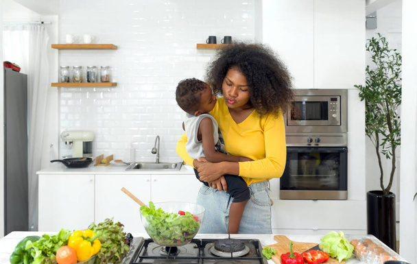 Mamá e hijo preparan alimentos frescos y nutritivos en una cocina iluminada por el sol, que incorporan vínculos familiares saludables y una vida saludable. - Foto, imagen