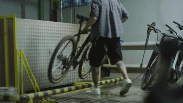 Volledige shot van de mens brengen fiets, het nemen van slang en wassen wielen en frame met water in de garage - Video