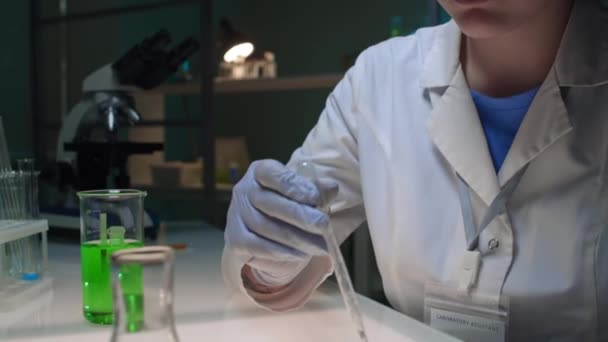 クローズアップタイルダウン 顔と義肢を持つ女性科学者の手,白いコートで細胞培養ソリューションを緑の基質でペトリ皿に落とし,バイオテクノロジーラボで研究 - 映像、動画