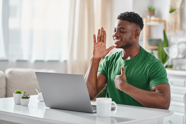 陽気なアフリカ系アメリカ人男性がラップトップでオンラインミーティング中にサイン言語でコミュニケーション - 写真・画像