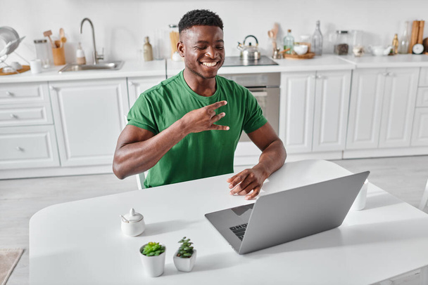 heureux sourd afro-américain pigiste en utilisant le langage des signes lors d'un appel vidéo sur ordinateur portable à la maison - Photo, image