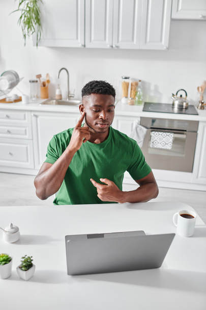 Sağır Afro-Amerikalı yeşil tişörtlü adam video çağrısında işaret dilini kullanıyor. - Fotoğraf, Görsel