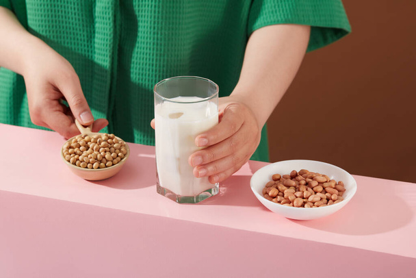 Жіноча модель рук тримає миску з сої та молочну чашку. Біла страва, що містить арахіс. Горіхи хороші джерела білка - Фото, зображення