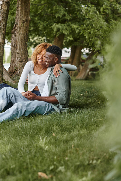 幸せなアフリカ系アメリカ人のカップルは,草の上に座っている間抱擁を着て,ロマンス - 写真・画像