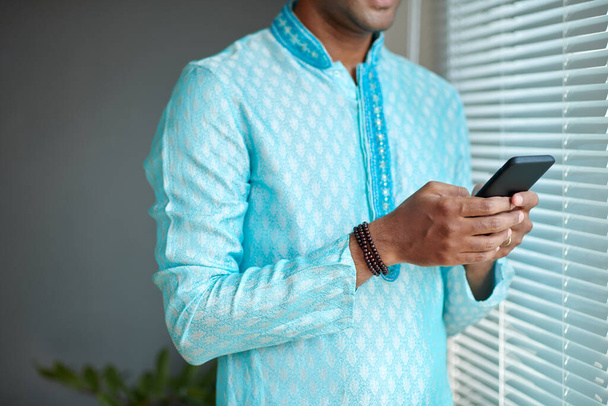 Indischer Mann in hellblauer Kurta beantwortet SMS auf Smartphone - Foto, Bild