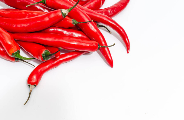 Detailní záběr parta dlouhých červených chilli papriček na bílém pozadí izolované. Leží diagonálně. - Fotografie, Obrázek