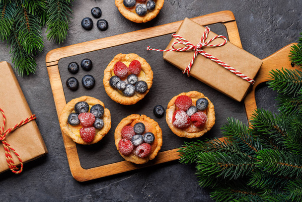 Праздничное наслаждение: рождественские кексы, украшенные ягодами. Плоский лежал - Фото, изображение